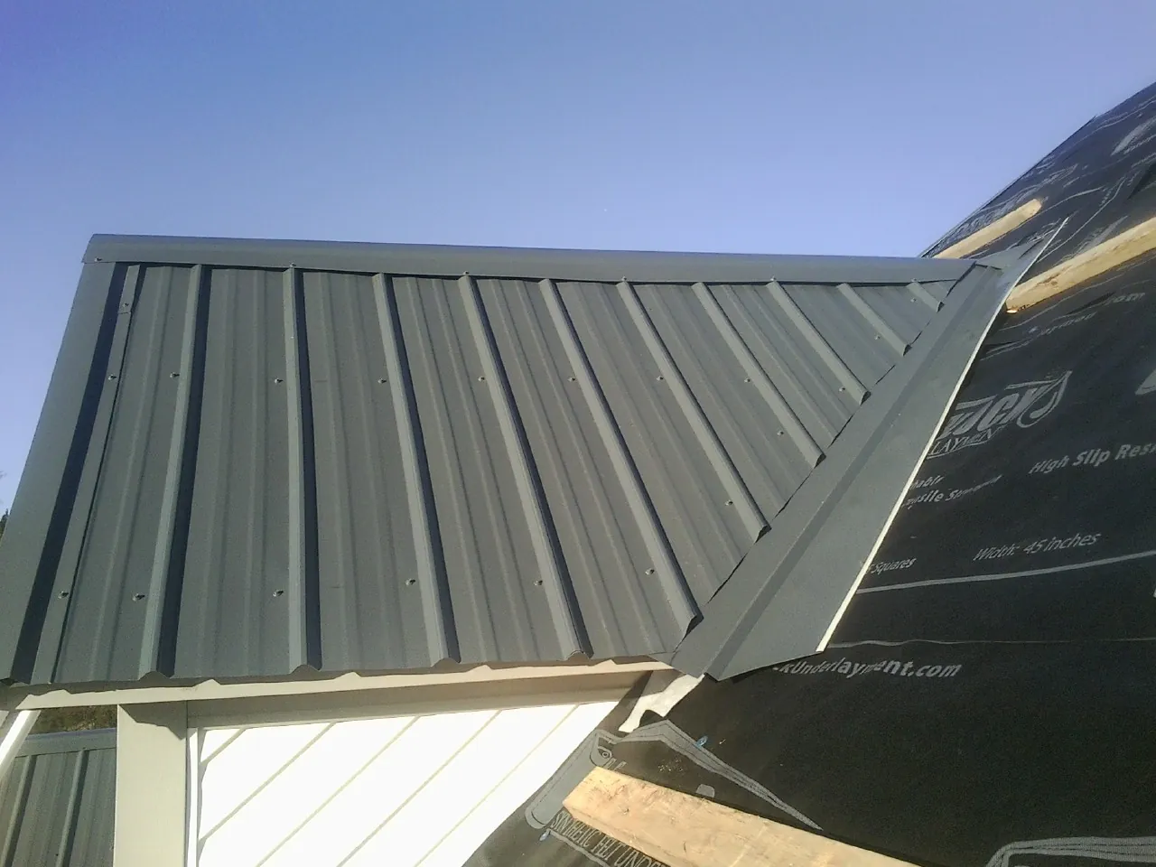 Gray metal roof panels going on over a garage gable in Juntura