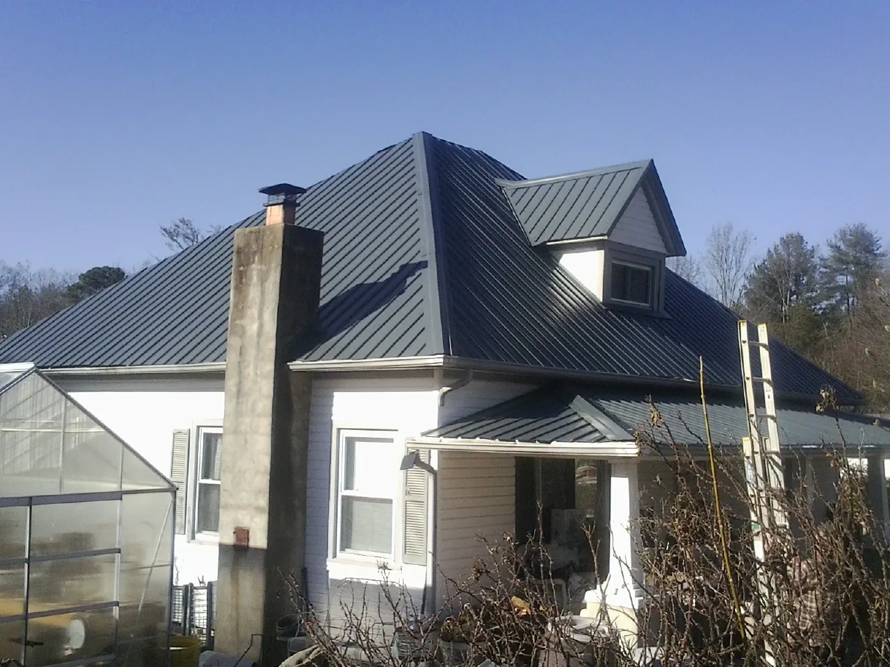 Dark blue standing seam metal roof on a white farmhouse with dormer — Slate & Tile Roof Repair by Roofing Brothers in Juntura