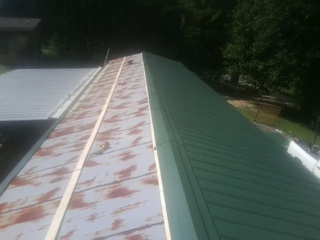 Old rusted panels beside newly installed green metal roofing — Wind Damage Roof Repair by Roofing Brothers in Juntura