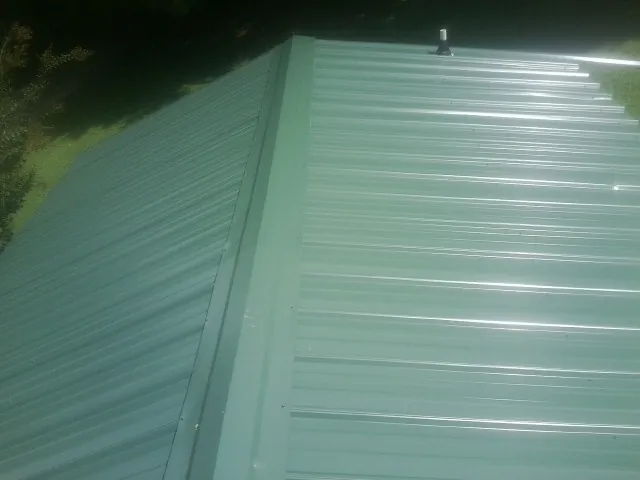 New green metal panels meeting at the ridge of a roof — Flat Roof Repair work by our crew in Juntura
