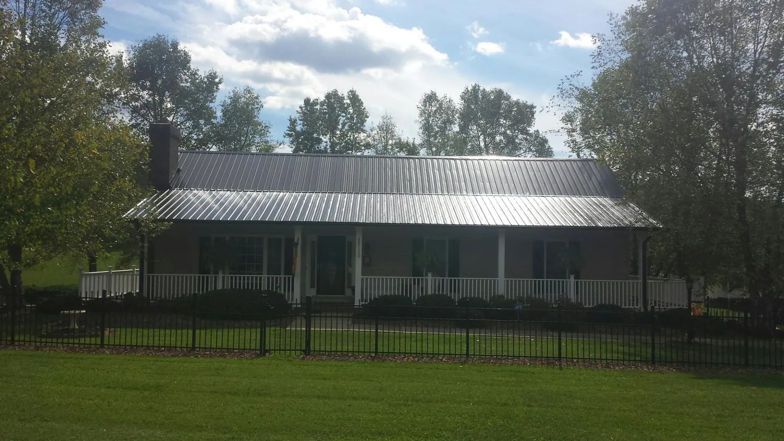 Gray metal roof on a brick ranch with a full width front porch — Gutter Guard Installation work by our crew in Juntura