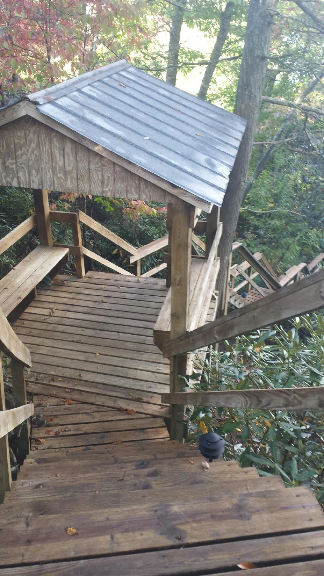Metal roofed shelter over wooden steps on a wooded walkway — Skylight Repair & Installation work by our crew in Juntura