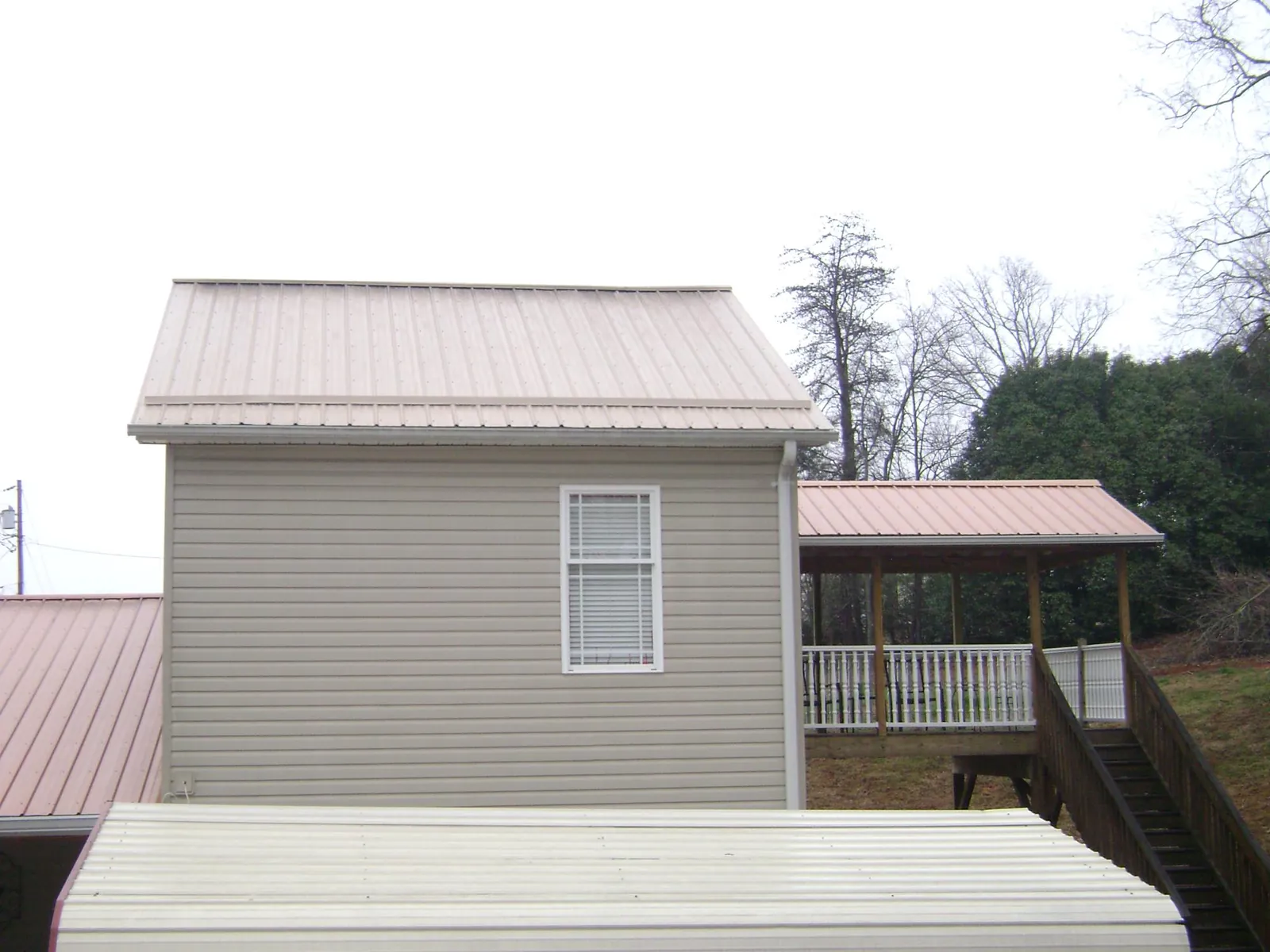 Tan metal roofs on a two story addition and attached porch, from a Roof Replacement job in Juntura
