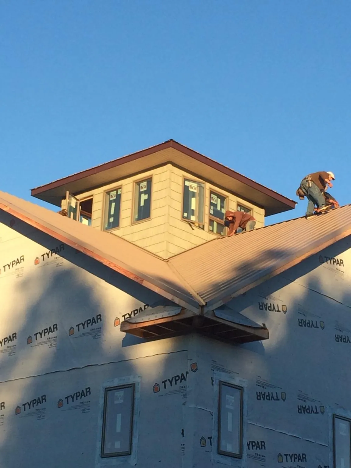 Roofers working around a rooftop cupola on a new metal roof at sunset — Roof Waterproofing in Juntura by Roofing Brothers